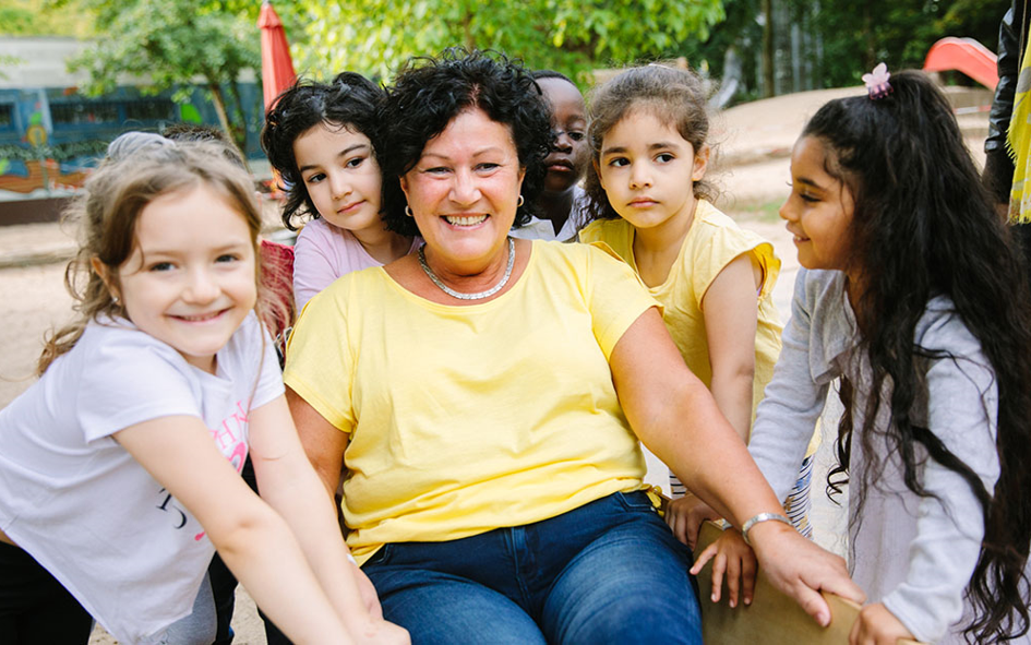 Bild: Eine Frau ist von Mädchen umrandet.